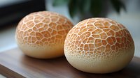 Two fresh cantaloupe melons with distinctive netted skin pattern sitting on wooden surface, ready for healthy eating and cooking applications.