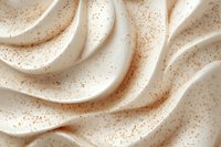 Smooth creamy waves with brown speckles creating soft flowing texture pattern in light beige tones, abstract background for food and cosmetic designs.