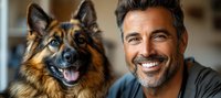 Mature man with gray beard and German Shepherd dog smiling at camera. Close up portrait showing bond between pet owner and loyal companion dog.