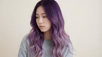 Young Asian woman with trendy purple ombre hair color looking down pensively. Modern hair styling and coloring concept for beauty salons and fashion.