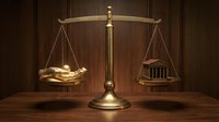 Golden scales of justice with money and courthouse symbol on wooden desk representing legal system balance between wealth and law enforcement.