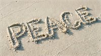 Word PEACE written in wet sand on a sunny beach, symbolizing harmony, hope, and tranquility by the sea.