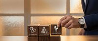 Professional businessman arranging wooden blocks with teamwork, collaboration and innovation icons on modern office desk with warm lighting.