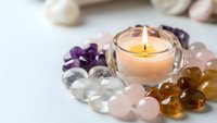 Healing crystals and gemstones arranged around glowing candle for meditation, spiritual wellness, chakra balancing and holistic therapy practices.