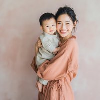 Happy Asian mother holding adorable baby boy in cozy home setting with warm natural lighting for family lifestyle photography and parenting content.
