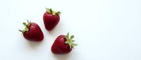 Three fresh ripe red strawberries with green leaves isolated on white background for healthy food design and culinary projects.
