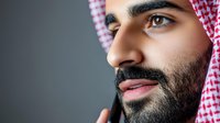 Middle Eastern man wearing traditional red and white keffiyeh headdress against dark background, close-up portrait showing strong facial features and well-groomed beard.
