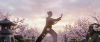 Young Asian man practicing tai chi martial arts in blooming cherry blossom park at sunrise with peaceful meditation pose and traditional exercise movement.