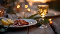 Romantic seafood dinner setting with grilled octopus, white wine glass, lemon slices and ambient bokeh lights creating intimate restaurant atmosphere.
