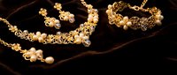 Elegant gold jewelry set with pearls and crystals on dark velvet background for luxury fashion and accessories display.