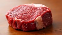 Fresh raw ribeye steak on wooden cutting board ready for grilling, premium beef cut with marbling for cooking and culinary preparation.