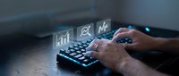 Business professional typing on keyboard with digital analytics icons floating above showing charts graphs and data visualization for corporate reporting.