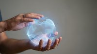 Male hands holding a glowing holographic energy sphere with blue light waves, futuristic technology concept on gray background.