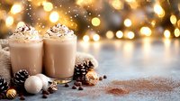 Creamy hot chocolate topped with whipped cream and cocoa powder, served with pine cones and Christmas ornaments against golden bokeh lights background.