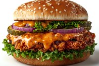Crispy chicken burger with melted cheddar cheese, fresh lettuce, red onion rings on sesame seed bun, close up view showing texture and layers.