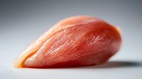 Fresh raw chicken breast fillet on light background with soft shadows, close up view showing meat texture and natural pink color for food photography.