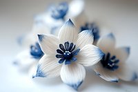 Delicate white and blue paper flower with intricate petals and detailed center creates elegant artistic composition on soft blurred background.