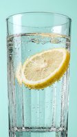 Glass of sparkling water with fresh lemon slice and ice bubbles, refreshing beverage for hydration, wellness and summer drinks.