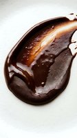 Melted dark chocolate with caramel swirl on white background, suitable for food, cosmetics, and culinary design projects.