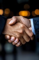 Close-up of firm business handshake between two professionals wearing suits, with warm bokeh lights in dark background, symbolizing trust and partnership.