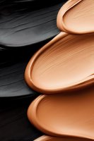 Smooth waves of liquid foundation makeup swatches in contrasting black and nude beige tones creating abstract textured pattern for cosmetic industry use.