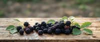 Fresh ripe blackberries with green leaves arranged on rustic wooden surface, suitable for food photography, culinary content, and healthy eating designs.