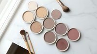 Professional makeup palette with neutral eyeshadow shades and brushes on marble surface for beauty and cosmetics applications.