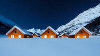 Cozy wooden chalets illuminated at dusk against snowy mountain backdrop, winter holiday resort lodges nestled in deep snow with dramatic alpine peaks.