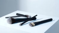 Professional makeup brushes set with black handles arranged on white surface for beauty and cosmetics applications.