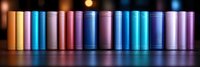 Colorful book spines arranged in row creating rainbow gradient effect against dark background with soft bokeh lights, panoramic composition for library or education themes.