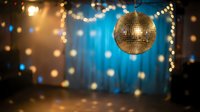 Golden disco ball hanging with warm bokeh lights and blue stage lighting creating festive party atmosphere for nightclub events and celebrations.