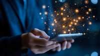Business professional holding smartphone with glowing digital network connections and light particles emerging from screen in dark blue environment.