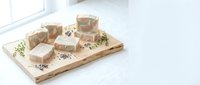 Handmade natural soap bars with dried herbs on wooden tray in bright minimalist bathroom setting for organic skincare and wellness routines.