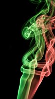 Abstract colorful smoke swirls in green and red hues flowing upward against black background creating dynamic motion effect for creative projects.