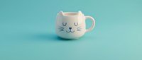 Adorable white ceramic cat mug with cute face design on turquoise background, perfect for coffee lovers and pet enthusiasts in kitchen decor.