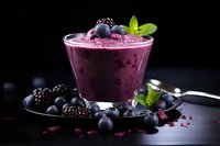 Purple berry smoothie with fresh blackberries and blueberries garnished with mint leaves on dark background, creamy texture and rich color for food photography.