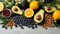Fresh organic produce arrangement with avocados, citrus, berries, nuts and herbs on gray background. Healthy eating and superfood concept for food design.