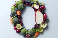 Fresh fruits and vegetables arranged in letter O shape with broccoli, berries, apples, carrots and kiwi on light gray background. Creative food typography.