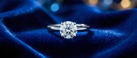 Elegant diamond engagement ring with brilliant cut stone in platinum setting on luxurious blue velvet jewelry box with bokeh lights background.