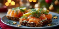 Festive smoked salmon canapés on dark bread with cream cheese and dill garnish, served on blue plate for holiday entertaining.