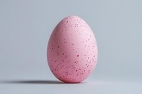 Pink speckled Easter egg isolated on light gray background, minimalist holiday decoration for spring celebrations.