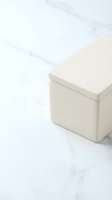 Minimalist cream colored storage box with lid on white marble surface for home organization and interior design projects.
