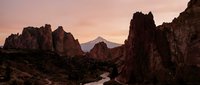 Dramatic rocky canyon landscape with winding river at sunset, towering stone formations creating natural gateway, warm golden light illuminating rugged terrain for travel and nature design projects.