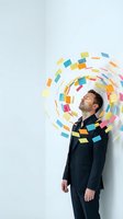 Businessman surrounded by colorful sticky notes in spiral motion representing creative brainstorming, innovation and organized workflow management.