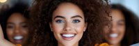 Young mixed-race woman with curly hair smiling confidently at camera with diverse female friends in background for teamwork and friendship concepts.