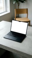 Modern laptop with blank white screen on concrete desk in minimalist home office workspace with wooden chair and natural light from window.