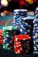 Stacks of poker chips in blue, red, and green colors on casino table with soft bokeh lights in background, showing gambling atmosphere and gaming concept.