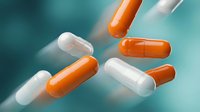 Orange and white pharmaceutical capsules floating in motion against turquoise background for medical healthcare and medication concepts.