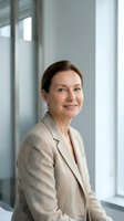 Professional mature businesswoman in beige suit smiling confidently in modern office environment with natural lighting for corporate communications.