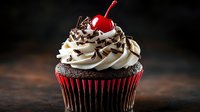 Chocolate cupcake with vanilla buttercream frosting, chocolate sprinkles and maraschino cherry on top against dark background. Food photography for bakery menu.